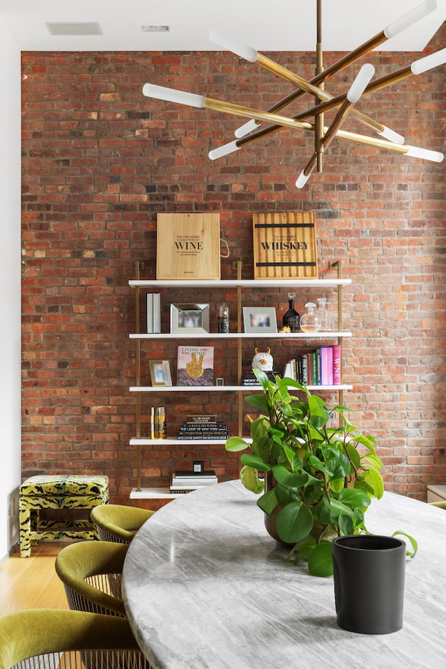 dining space with wood finished floors and brick wall