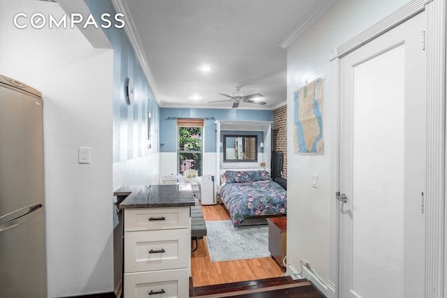 bedroom featuring crown molding, freestanding refrigerator, light wood finished floors, and ceiling fan