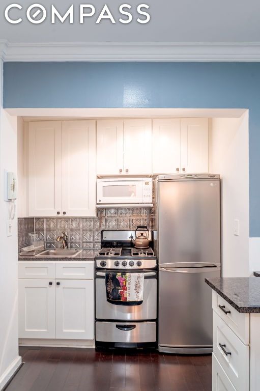 kitchen featuring white cabinets, appliances with stainless steel finishes, decorative backsplash, and dark stone countertops