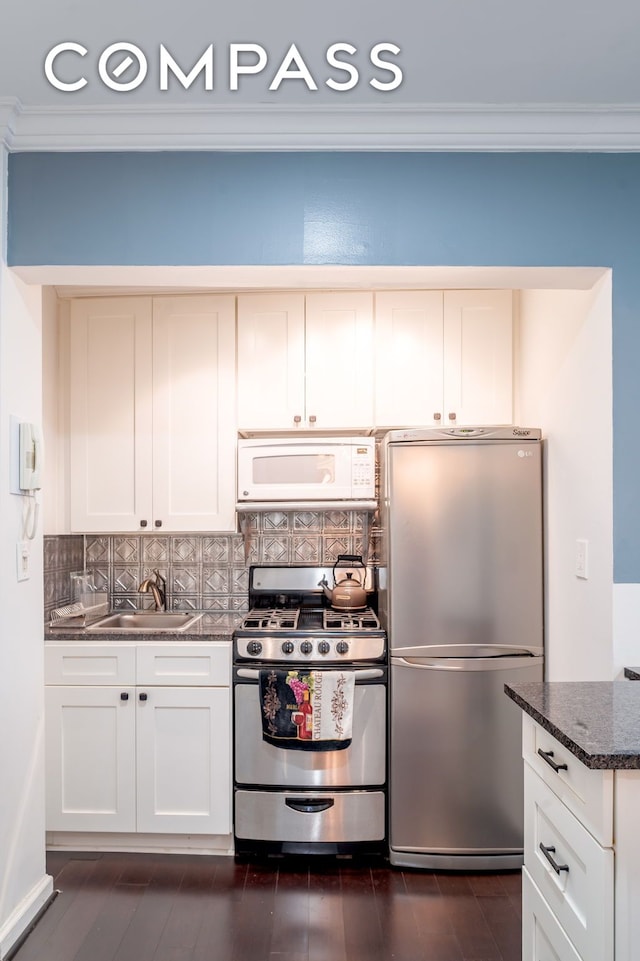 kitchen with crown molding, backsplash, appliances with stainless steel finishes, white cabinets, and a sink