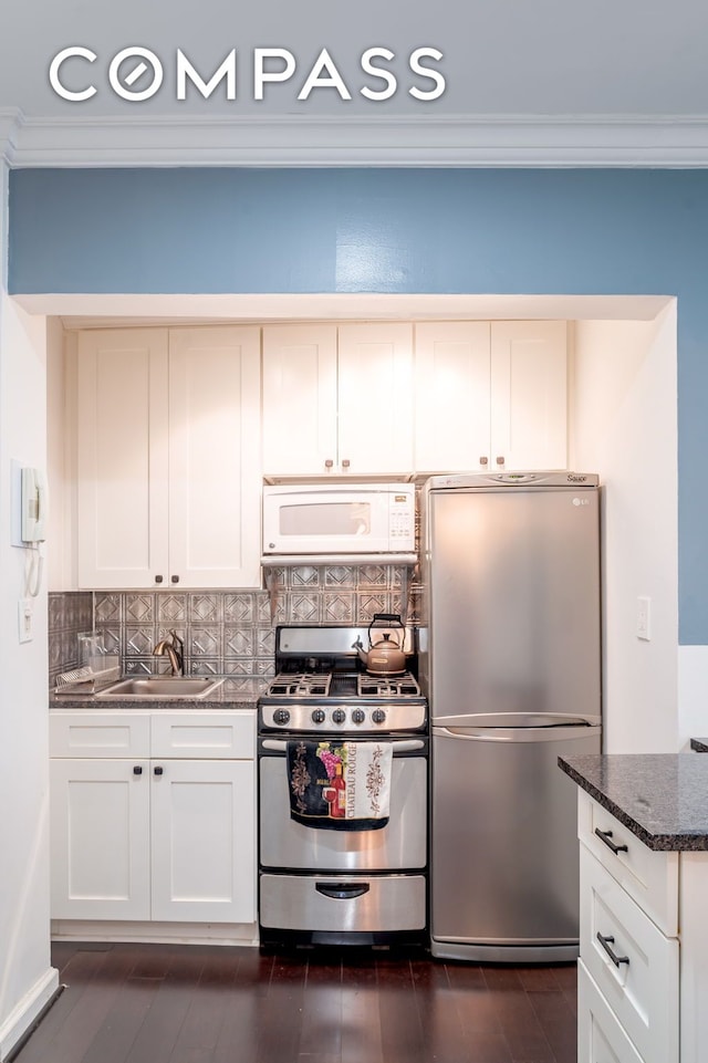 kitchen with decorative backsplash, ornamental molding, white cabinets, a sink, and appliances with stainless steel finishes