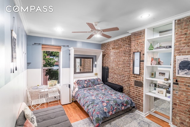 bedroom featuring ornamental molding, ceiling fan, wood finished floors, and brick wall