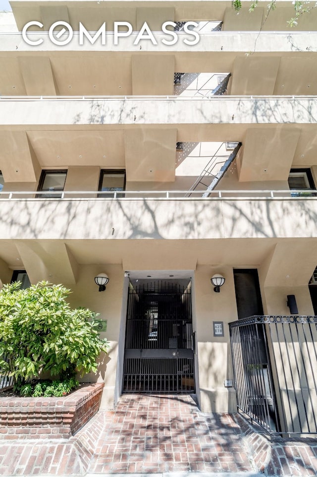 view of exterior entry with a balcony and stucco siding