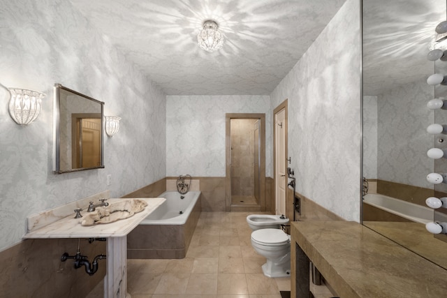 bathroom featuring tiled bath, tile patterned floors, toilet, and a bidet