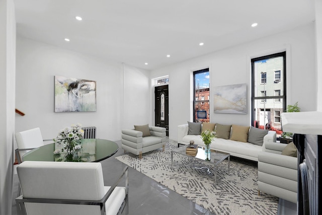 living area featuring finished concrete flooring, radiator heating unit, and recessed lighting