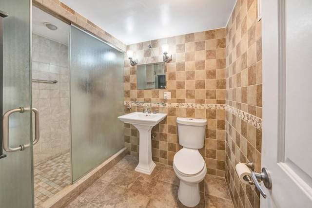 bathroom with a shower with shower door, tile walls, and toilet