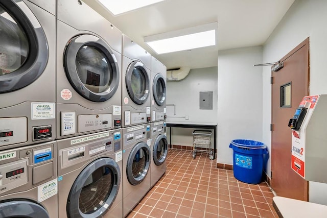 laundry room with light tile patterned floors, stacked washer / dryer, washing machine and clothes dryer, and electric panel