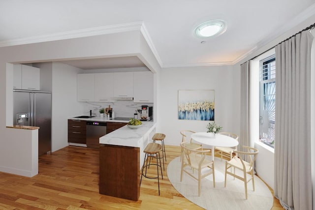 kitchen featuring stainless steel dishwasher, built in refrigerator, ornamental molding, and dark brown cabinetry