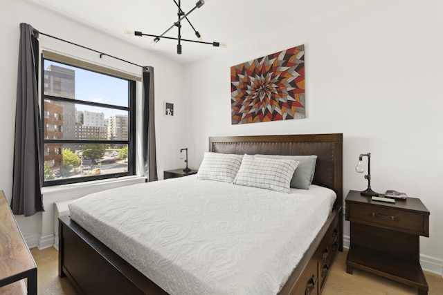 bedroom featuring an inviting chandelier and light hardwood / wood-style floors