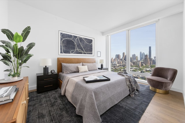 bedroom with dark wood finished floors, a view of skyline, and baseboards