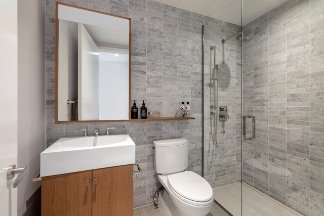 bathroom featuring tile walls, a stall shower, toilet, and vanity