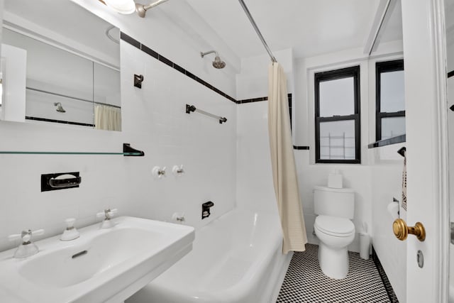 full bath with toilet, tile patterned floors, a sink, shower / bath combination with curtain, and tile walls