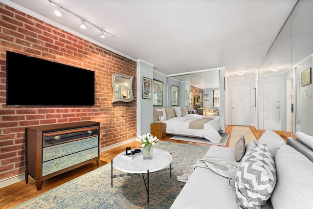 living room featuring a brick fireplace, hardwood / wood-style flooring, rail lighting, and brick wall