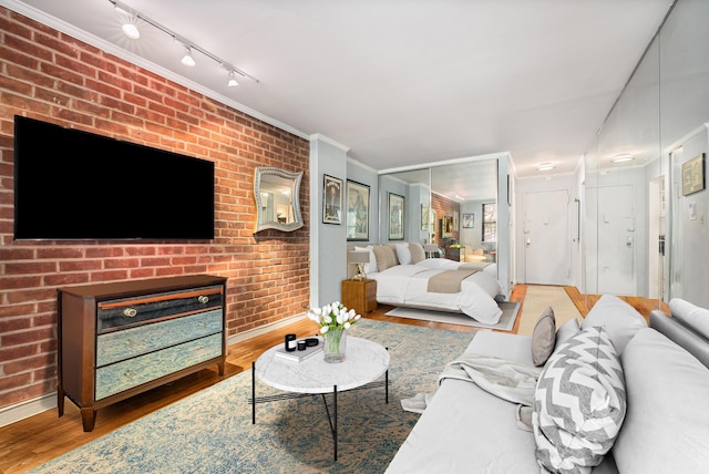 living room with brick wall, a fireplace, wood finished floors, baseboards, and ornamental molding