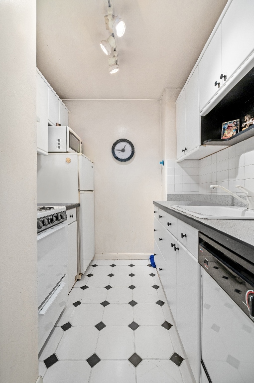 kitchen with white cabinetry, sink, backsplash, and white appliances