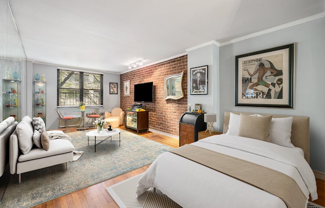 bedroom with brick wall, crown molding, and wood finished floors