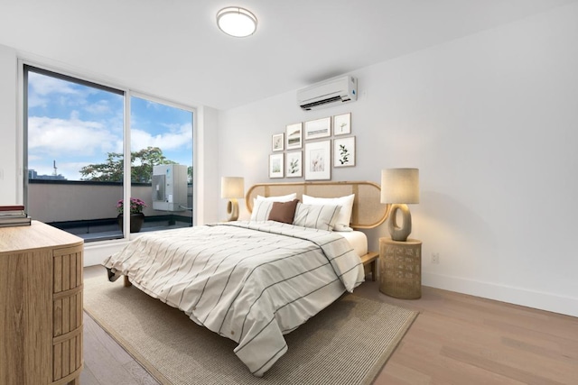 bedroom featuring access to exterior, a wall unit AC, and light wood-type flooring