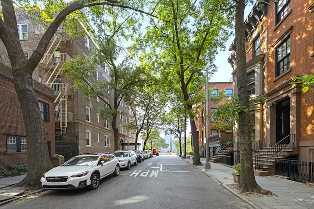 view of asphalt street with sidewalks, curbs, and street lighting