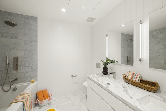 full bathroom featuring tile patterned flooring, wooden walls, vanity, tiled shower / bath, and toilet