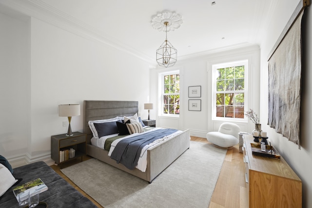 bedroom featuring light wood-type flooring, baseboards, ornamental molding, and a chandelier