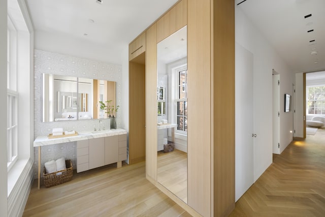 hallway with a sink, parquet floors, and wallpapered walls