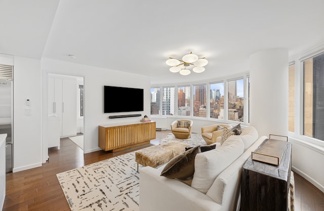 living area with dark wood-type flooring, baseboards, and a chandelier