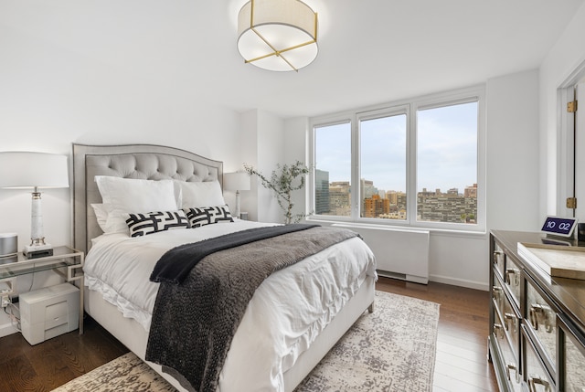 bedroom with baseboards, a city view, and wood finished floors