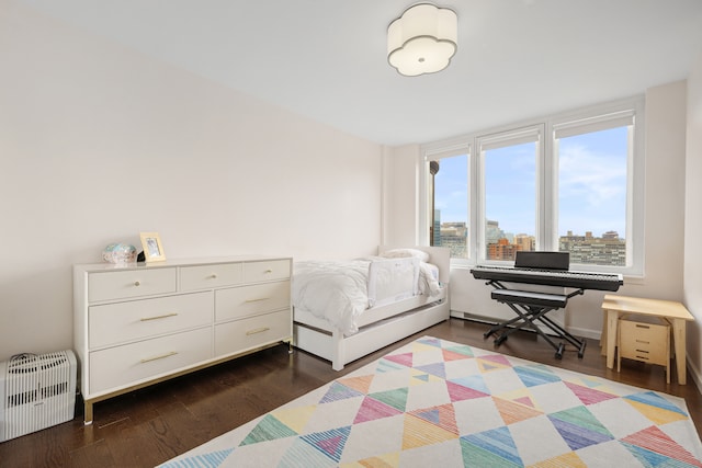 bedroom featuring dark wood-style flooring, a city view, and radiator heating unit