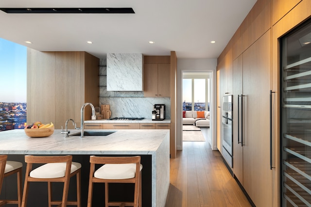 kitchen featuring modern cabinets, a sink, wine cooler, a breakfast bar area, and backsplash