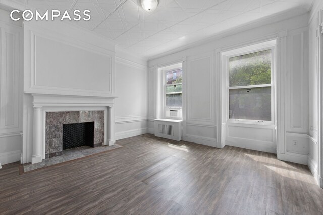 unfurnished living room featuring dark wood-type flooring, a premium fireplace, and radiator