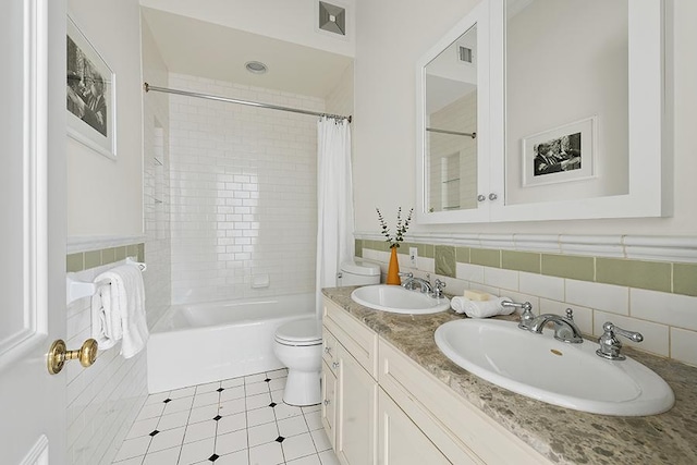 full bath with tile walls, toilet, shower / tub combo with curtain, and a sink