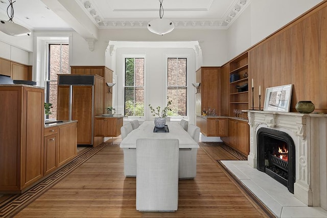 dining room featuring a warm lit fireplace, wood finished floors, and crown molding