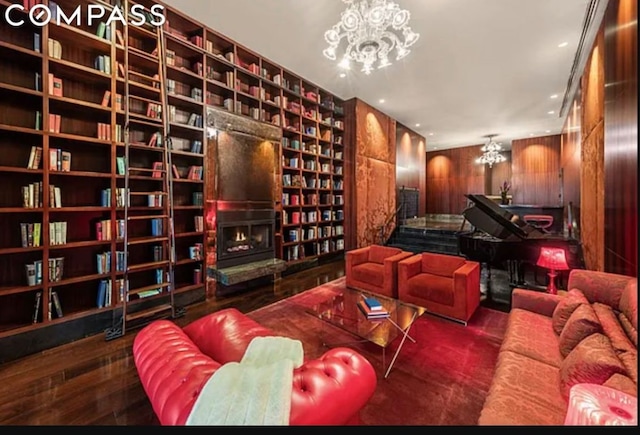 cinema room with built in features, a large fireplace, wooden walls, and a chandelier