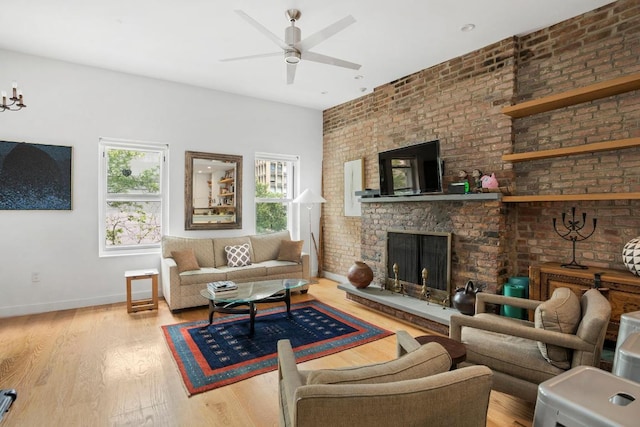 living room with ceiling fan, brick wall, a fireplace, and light hardwood / wood-style flooring