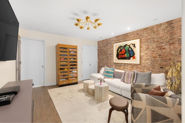 kitchen with brick wall, appliances with stainless steel finishes, white cabinetry, sink, and light hardwood / wood-style flooring