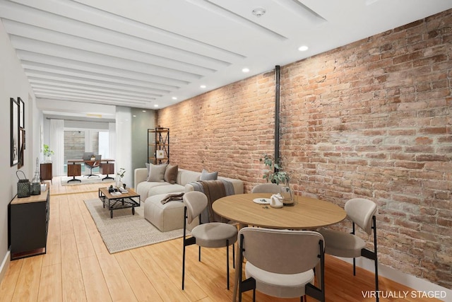 dining space featuring brick wall and light wood-type flooring