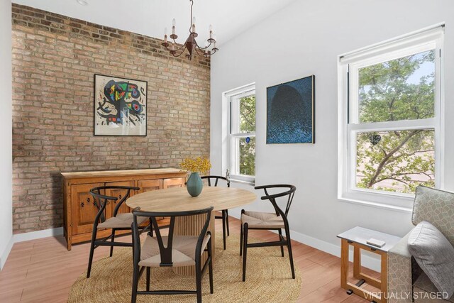 dining space featuring brick wall and light wood-type flooring