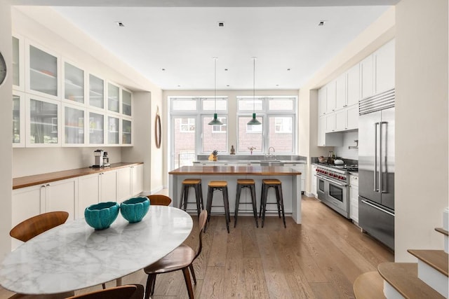 kitchen featuring high quality appliances, decorative light fixtures, a kitchen island, and white cabinets