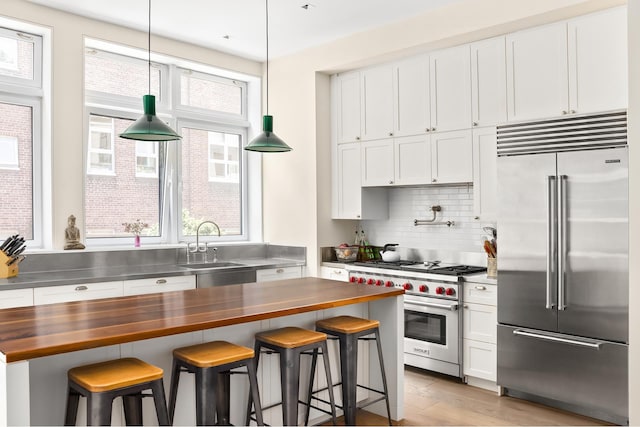 308 E 30th St Unit 1, New York City, NY 10016 - kitchen featuring high quality appliances, butcher block countertops, backsplash, and white cabinets