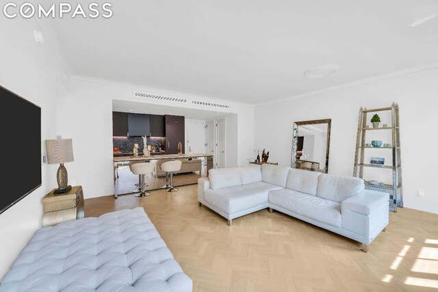 living room with light parquet flooring, sink, and crown molding