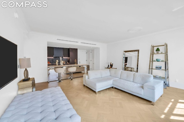 living room with light parquet floors, ornamental molding, and sink