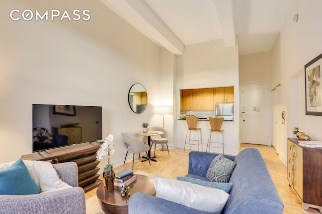 living room featuring a high ceiling, baseboards, and beam ceiling