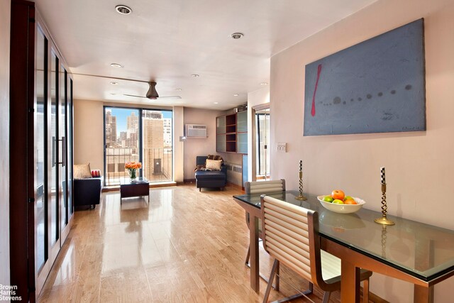 living room featuring ceiling fan, radiator, a wall mounted AC, and light hardwood / wood-style floors