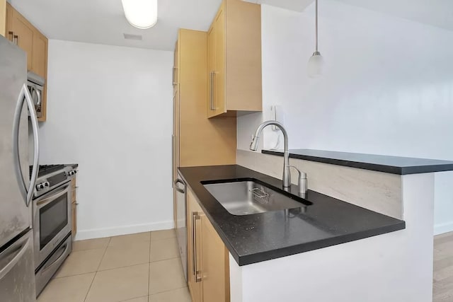 kitchen featuring stainless steel appliances, light brown cabinetry, sink, hanging light fixtures, and light tile patterned flooring