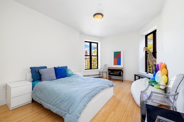 bedroom with radiator heating unit and light wood-style flooring