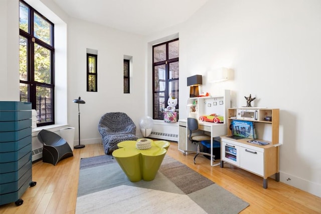 living area featuring a baseboard heating unit and light wood-type flooring