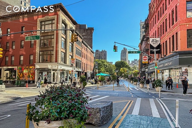 view of street with curbs, traffic signs, a city view, street lights, and sidewalks