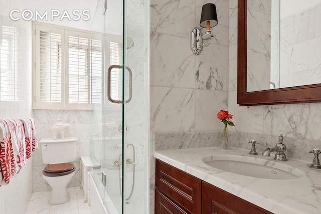 bathroom featuring tile walls, toilet, enclosed tub / shower combo, marble finish floor, and vanity