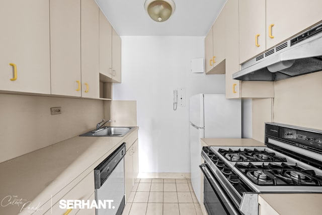 kitchen featuring dishwasher, sink, light tile patterned floors, gas range, and cream cabinets