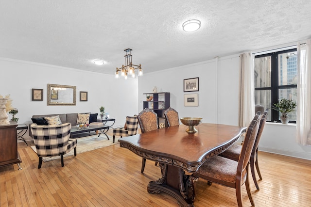 dining space featuring a notable chandelier, a textured ceiling, and light wood-type flooring